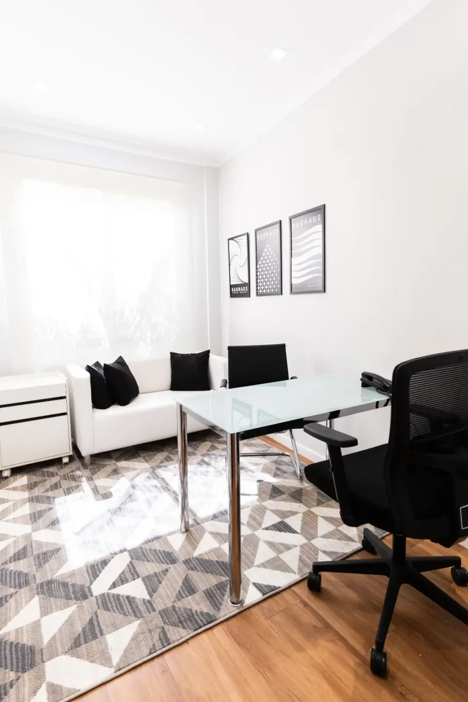 Consultório com mesa de atendimento e sofá, iluminado por luz natural